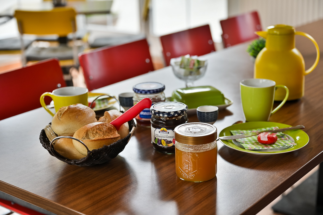 Gedeckter Frühstückstisch mit Brötchen, Honig und Kaffee